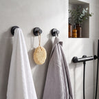 Trois crochets Murovea noir mat dans une douche : serviette, éponge et peignoir